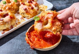 Dipping a mini pizza bagel into a small bowl of marina.