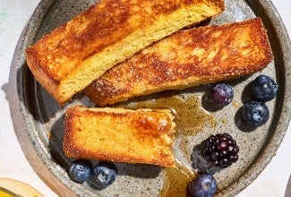 French Toast Sticks on a plate with fresh berries and maple drizzle.