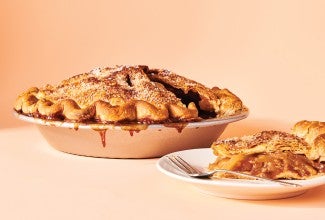 An apple pie in a pie tin and a slice on a plate.
