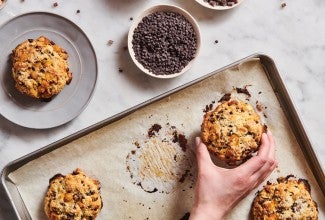 Baker picking up scones baked on a parchment-lined baking sheet