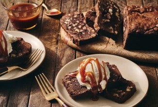 A sliced Brownie Loaf on a plate with vanilla ice cream and a caramel swirl