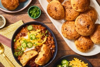 Gluten-Free Bacon Cheddar Rolls on a platter with a bowl of chili next to it. Seen from above.