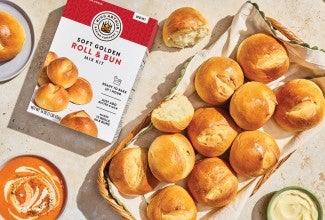 Soft Golden Buns & Rolls in a basket on a table with a box of King Arthur Baking Soft Golden Buns & Rolls mix