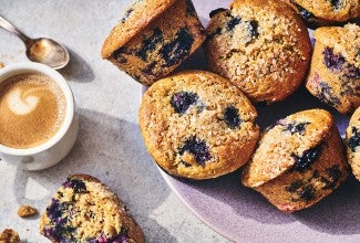 Sourdough Discard Blueberry Muffins on a counter with a cup of coffee in the frame.