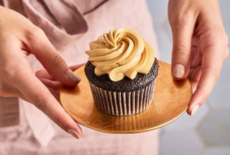 Holding a plate with a Chocolate Cupcake with Whipped Caramel Frosting on it