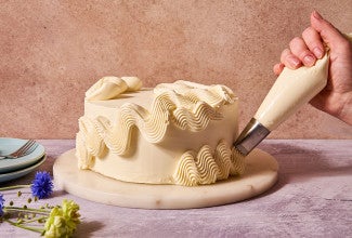 Piping Italian Buttercream onto a cake.
