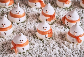 Snowman Meringues arranged on a counter with sugar snow