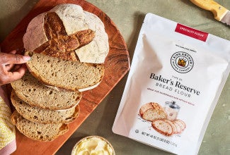 Bag of Baker's Reserve Bread Flour next to a loaf of artisan bread