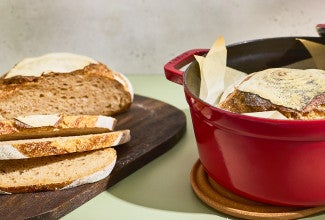 Crusty Dutch Oven Sourdough Bread sliced on a cutting board and shown in a dutch oven