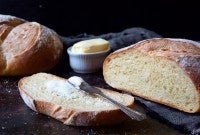 Loaves of sourdough bread on a cutting board, one loaf sliced.