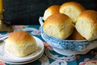 Golden soft dinner rolls in a bowl, one on a bread plate.