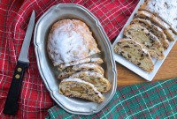 Two loaves of Christmas Stollen, sliced on plates on a table.