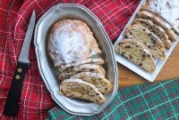 Two loaves of Christmas Stollen, sliced on plates on a table.