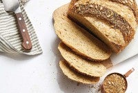 Sliced seeded sourdough next to cup of grains