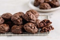 A pile of double chocolate chip cookies on a cooling rack.