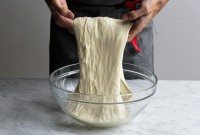 Baker using hands to fold bread dough