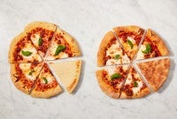 Two pizzas next to each other, one with a darker underside of the crust