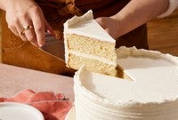 Baker cutting a slice of white velvet cake