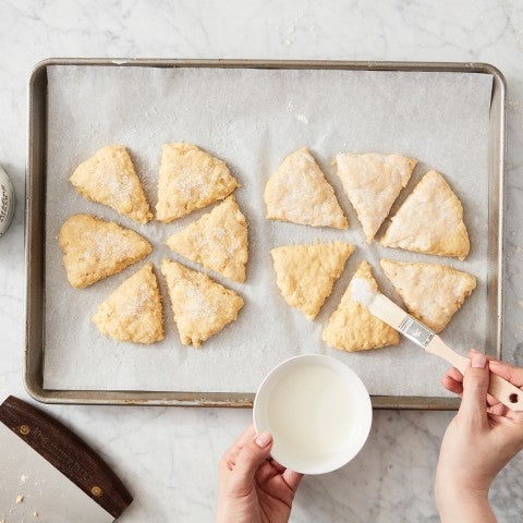 Unbaked scones being brushed with milk - select to zoom