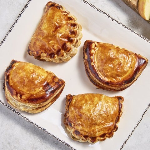 Overhead view of four chausson pastries showing golden and dark brown glossy tones. - select to zoom