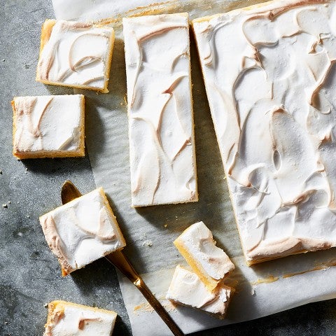 Overhead photograph of lemon meringue bars with various shapes sliced and scatter on a counter. - select to zoom