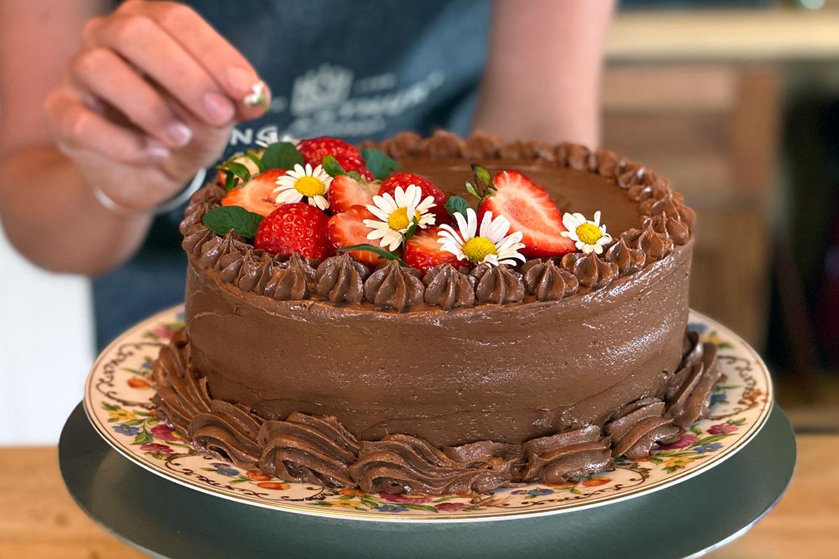 A chocolate cake decorated with edible flowers and berries