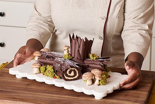 Chocolate Buche de Noel with Cookie Butter Whipped Ganache on a white platter.