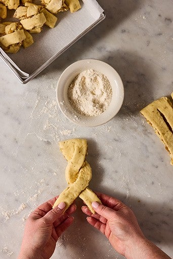 Twisting french onion roll dough before rolling it into a knot.