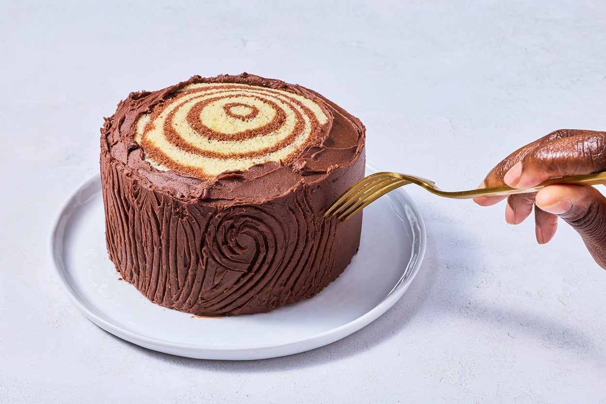 Drawing lines with a fork into chocolate frosting on the outside of Souche de Noël cake to give the appearance of tree bark.