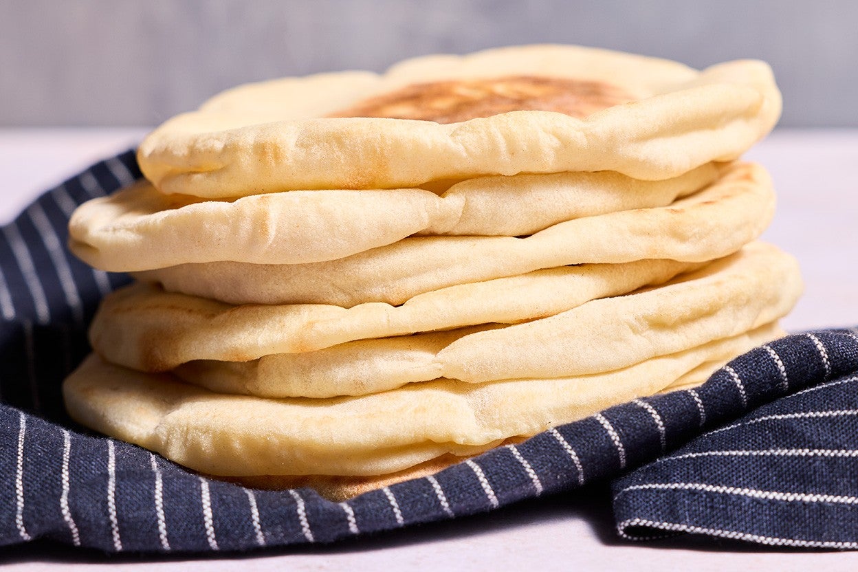 Stack of Sourdough Pita Bread on a dark blue napkin with stripes, photographed from the side.
