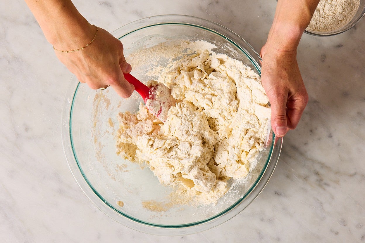 Stirring biscuit dough with a spatula in a bowl.