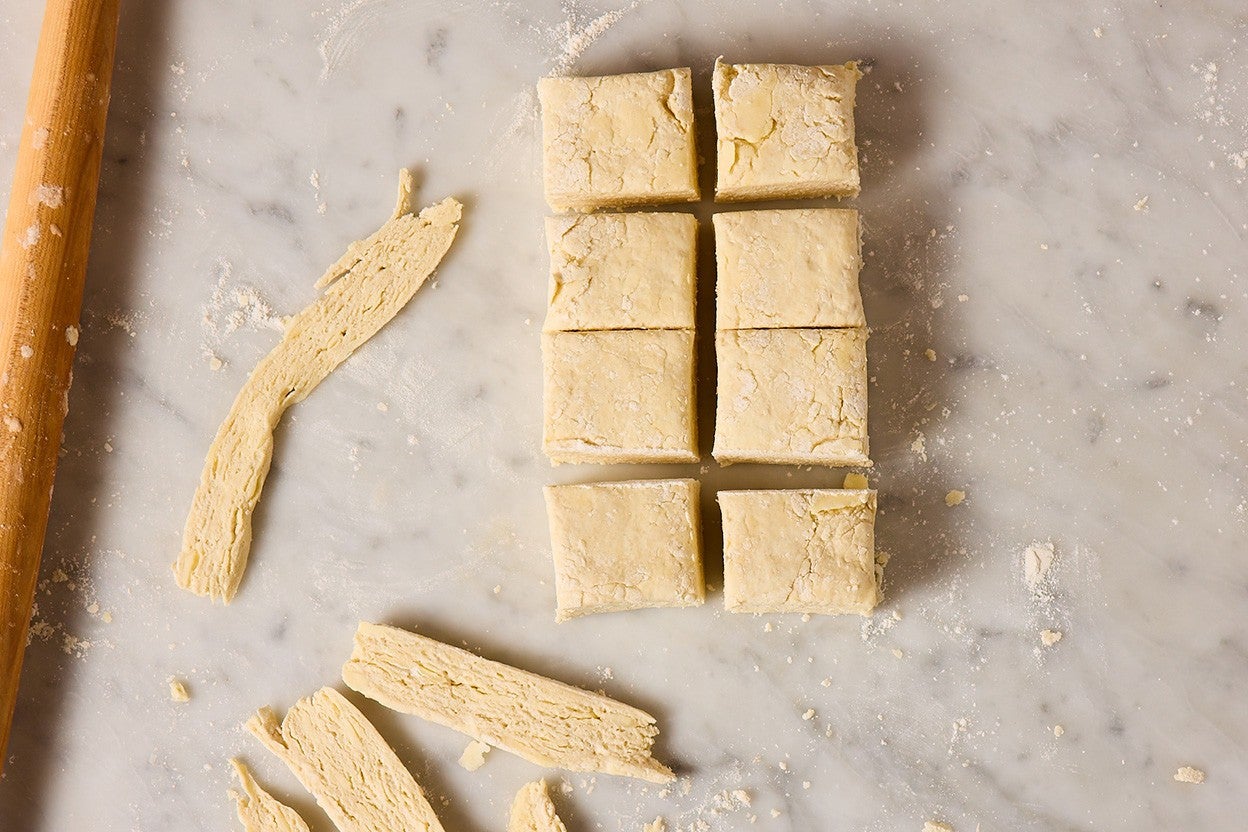 Looking down on 8 cut and trimmed raw biscuits, trimmed and ready to be baked.