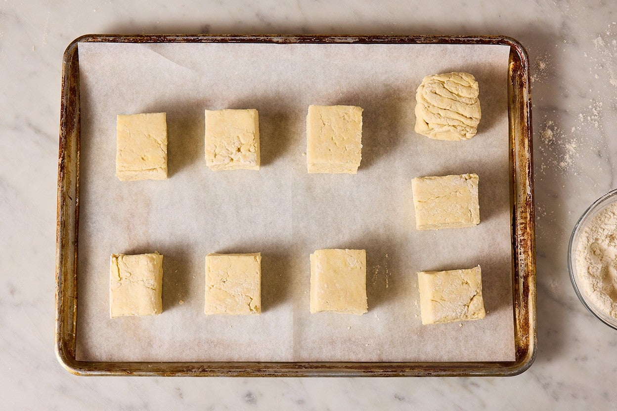 A baking sheet lined with parchment paper holding nine biscuits arranged with plenty of space.