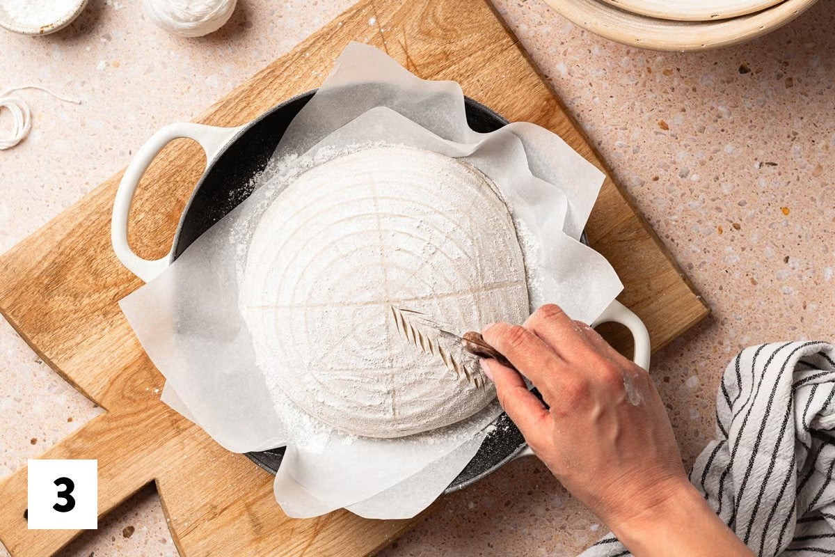Cutting a wheat pattern into a loaf of sourdough dough with a lame