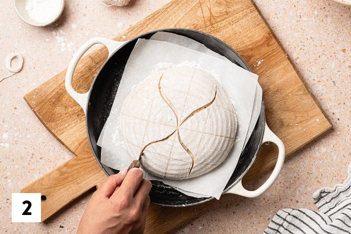 Scoring four S patterns into a gridded sourdough loaf