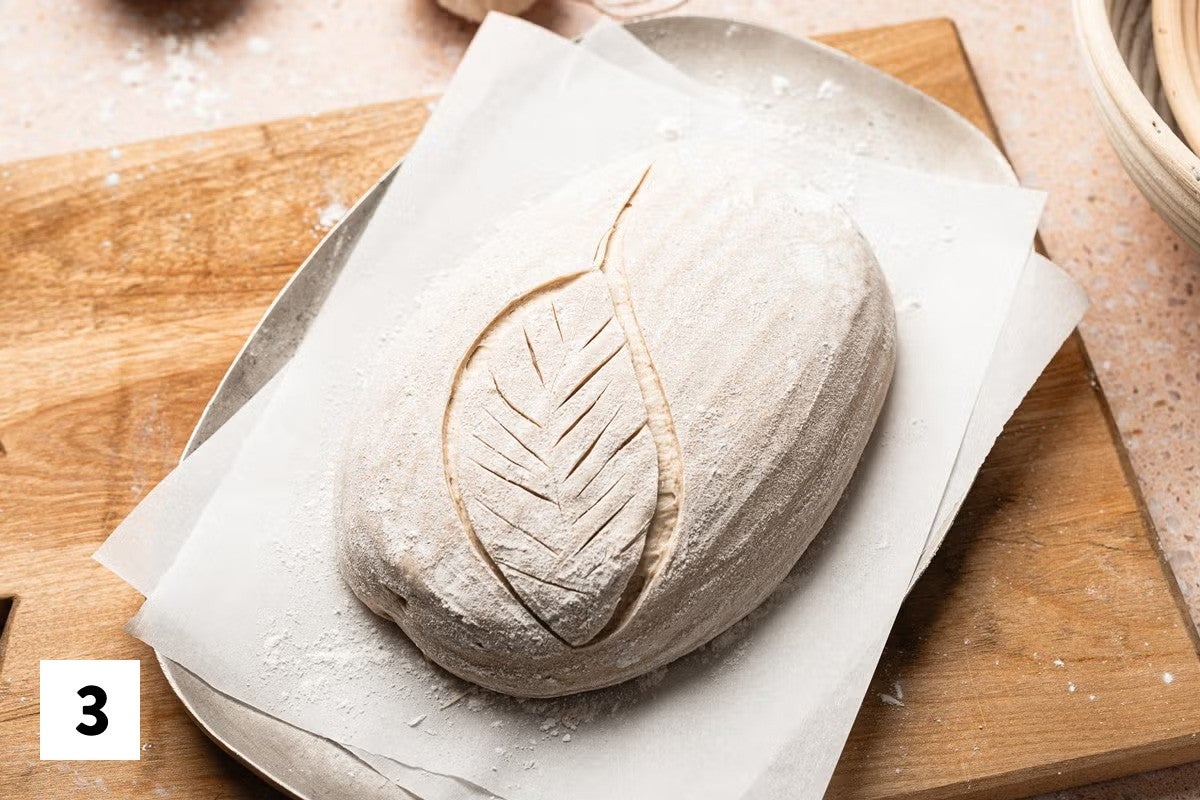 Sourdough bread loaf with part of a leaf design scored into it 