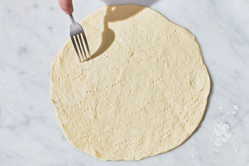 Pricking a flatbread with a fork prior to baking.