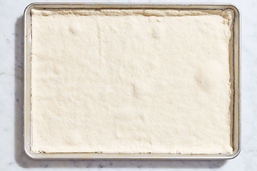 Gluten-Free pizza dough after rising in the sheet pan before baking.