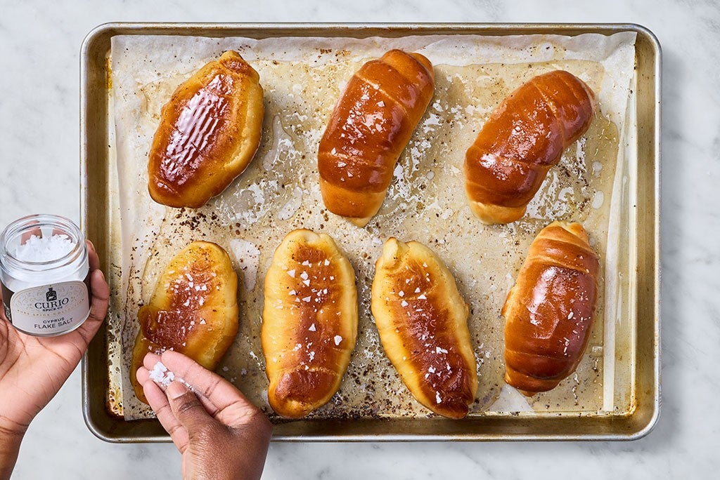 Sprinkling sea salt on salt bread during the baking process.
