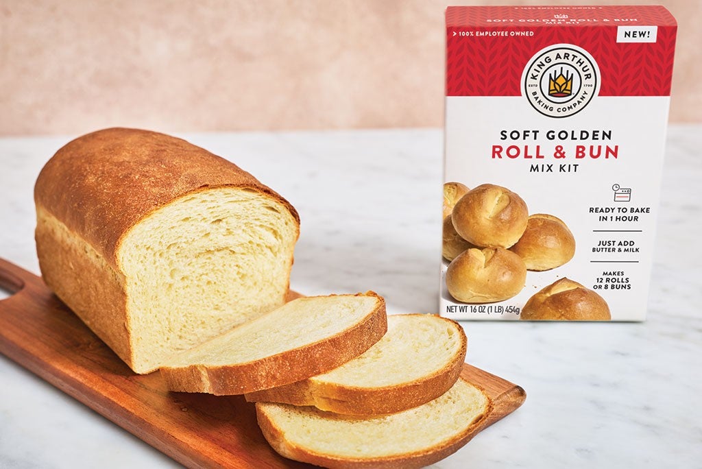 A sliced loaf of bread and a box of King Arthur Baking Soft Golden Roll & Bun Mix