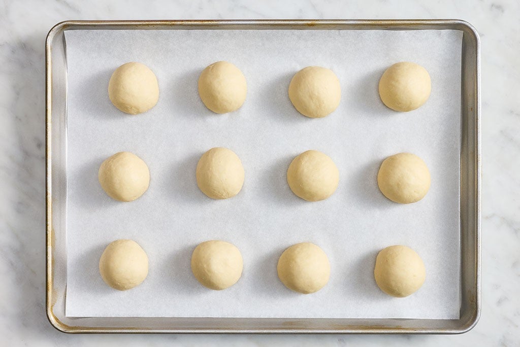 12 Roll dough balls on a parchment lined baking sheet organized neatly