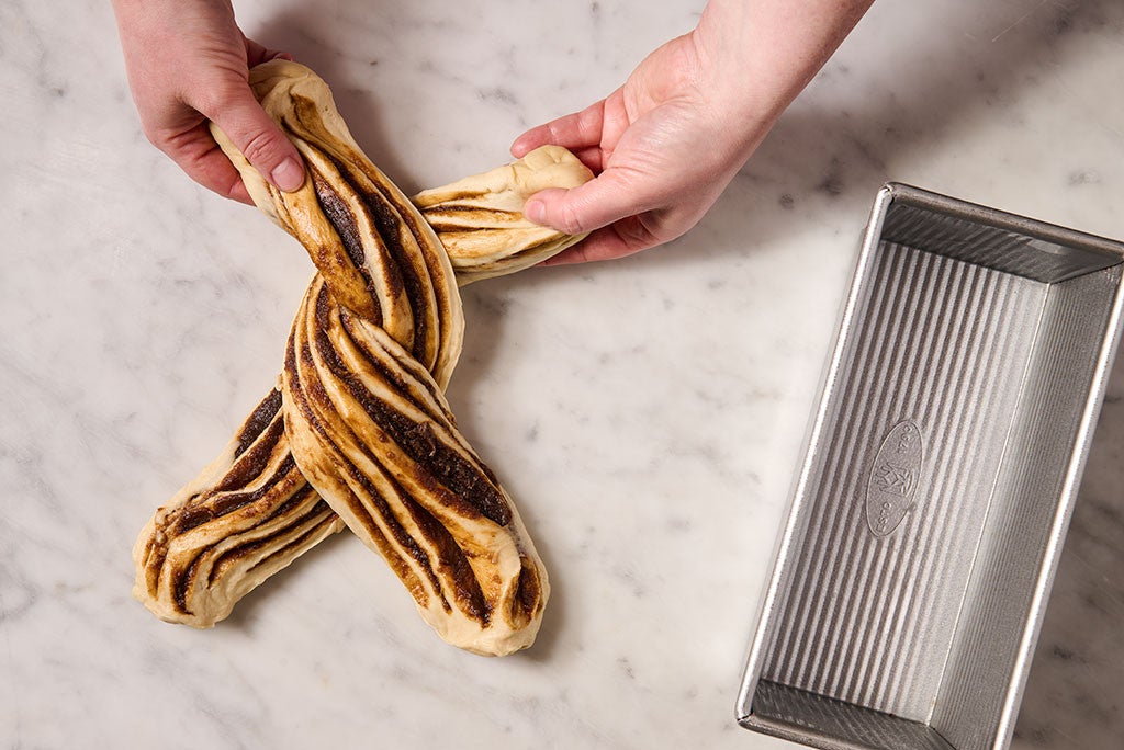 Twisting two pieces of sliced cinnamon babka bread dough