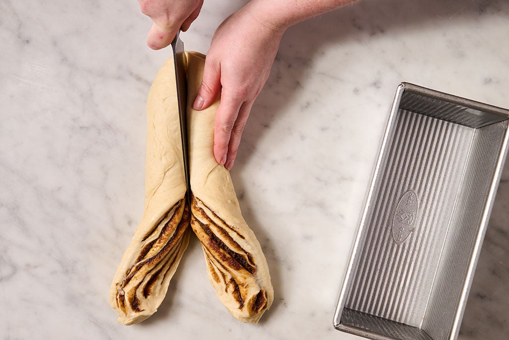 Cutting cinnamon babka dough in half with a knife
