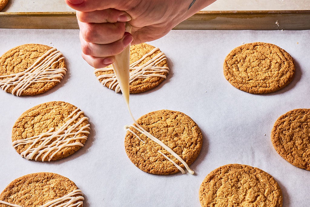 Drizzling icing onto the tops of Crispy Brown Butter Cookies