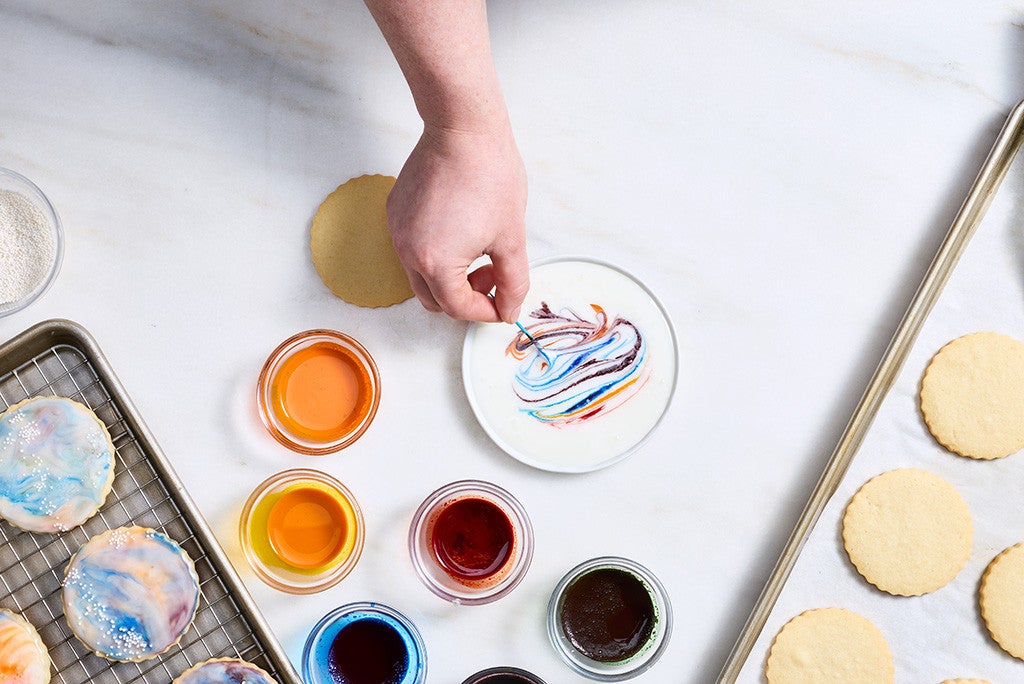 Adding streaks of color with a toothpick to white icing