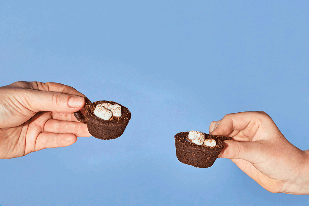 Tapping two Hot Cocoa Cookies together for a cheers moment