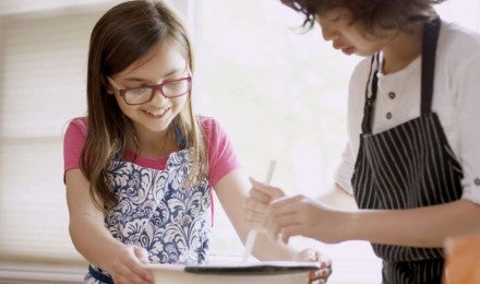 Two children mixing dough in a bowl