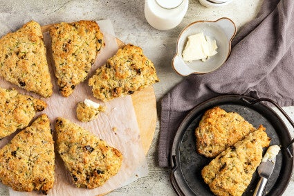 Zucchini scones on a piece of parchment paper with two on a small plate next to a bowl of butter