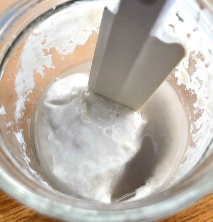 stirring dark liquid into starter in a jar