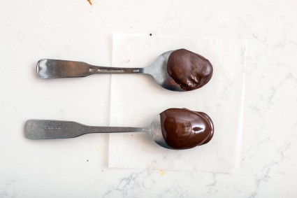 Two spoons dipped into chocolate, one that's shiny and in temper and one that's dull and not properly tempered
